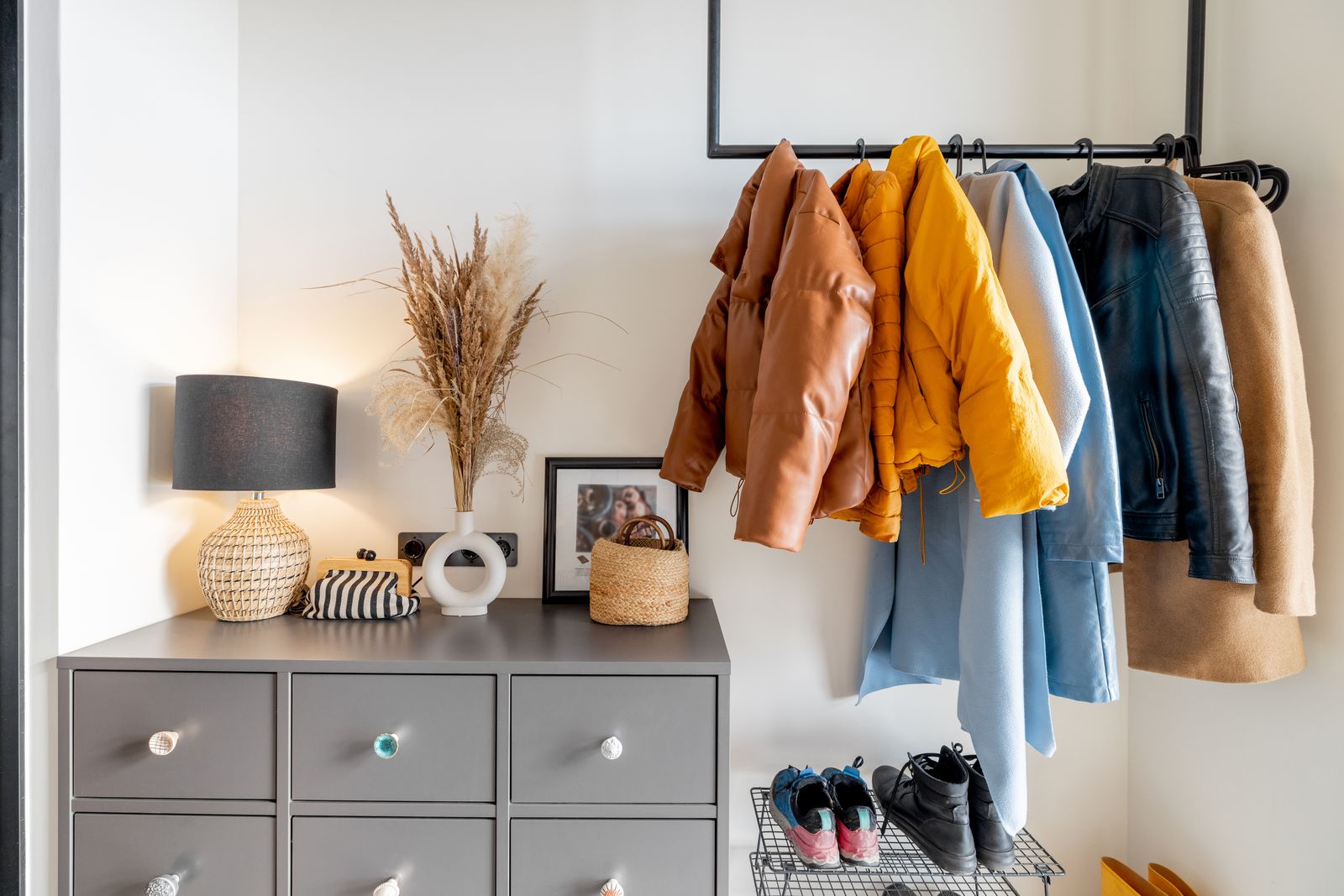 Garderobe im Eingangsbereich: Jacken an Haken über einer Kommode, daneben abgestellte Schuhe