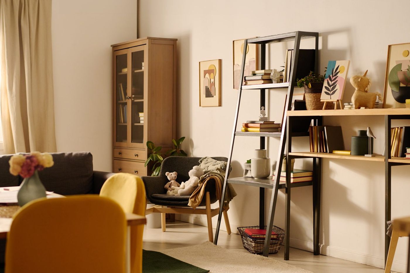 Wohnzimmer mit Leiterregal, Sessel und Vitrine in warmem Licht