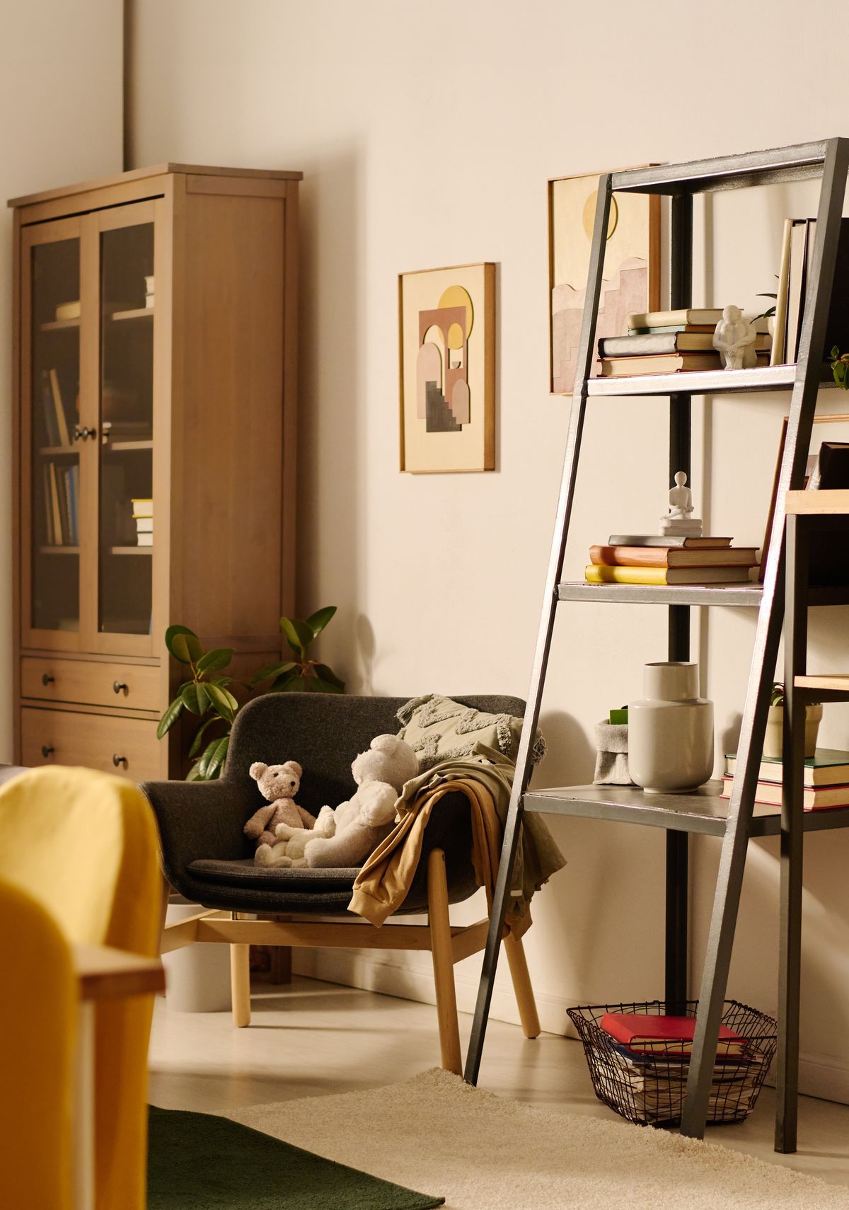 Wohnzimmer mit Leiterregal, Sessel und Vitrine in warmem Licht