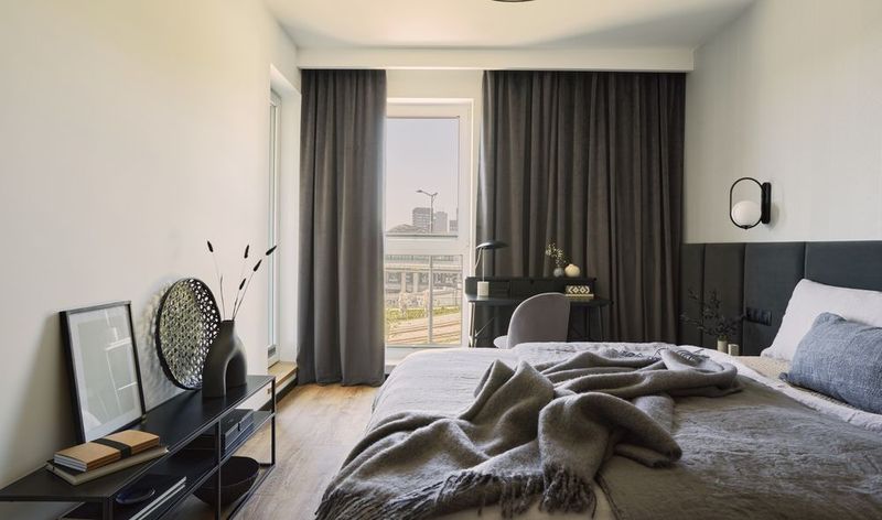 Schlafzimmer mit grauer Bettwäsche und Blick über die Stadt